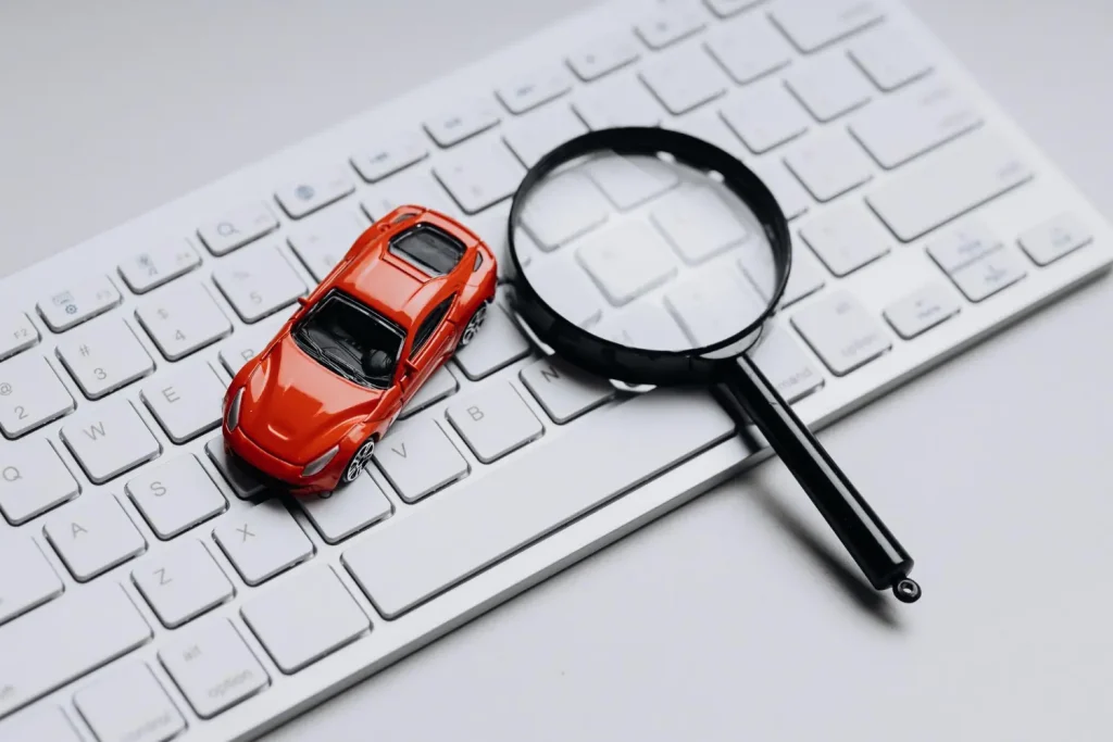 Carro em miniatura e lupa sobre teclado representando SEO local no marketing automotivo