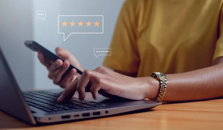 Pessoa usa celular e notebook com balão de cinco estrelas na tela, representando avaliações no Google de clientes