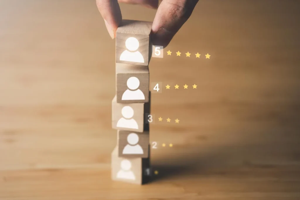Mão empilha cubos de madeira com ícones de clientes e notas de 1 a 5 estrelas, ilustrando o ICP no marketing
